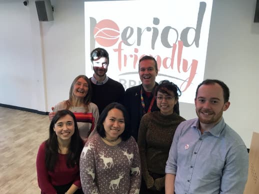 A group of 4 women and 3 men standing in front of a screen with the period friendly Bristol logo. They are standing close together, smiling.